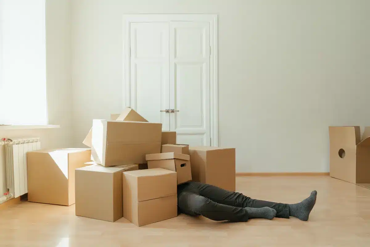 Empty bright apartment living room with moving boxes, parquet floor, white walls and doors