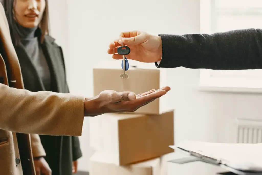 Two people exchanging apartment keys during handover in bright modern interior
