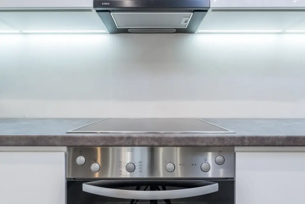 Clean modern kitchen with white cupboards, black countertop and open oven