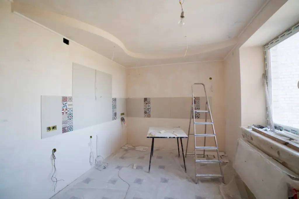 Renoviertes Zimmer mit weißen Wänden, Holzdielen und Renovierungsmaterialien, feiner Staub sichtbar.