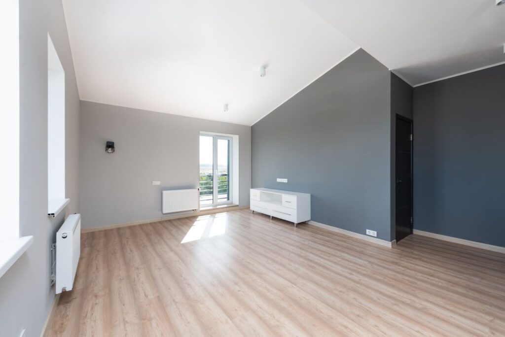 Leere, helle Wohnung mit Holzboden und großen Fenstern