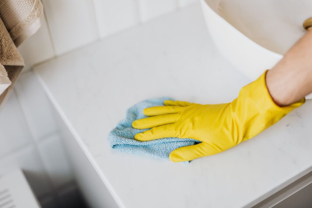 Hand in Gummihandschuh wischt eine Fläche gründlich ab